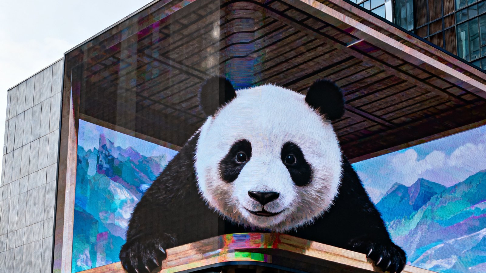 成都春熙路太古里商圈建筑外墙上安装的OG视讯裸眼3D大屏，白天的自然光下屏幕依然清晰鲜艳，正在展示一只大熊猫从屏幕中探出脑袋的3D动画